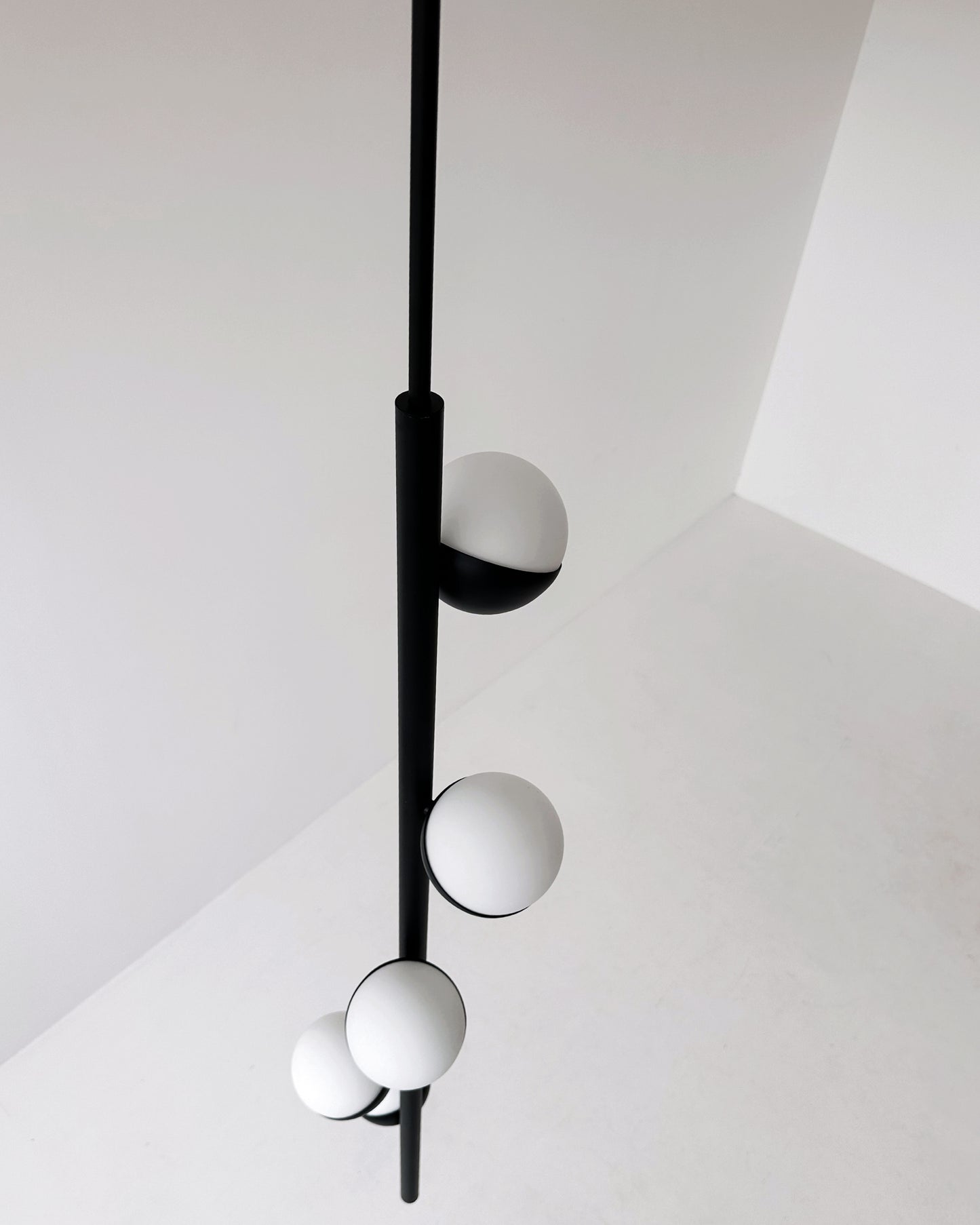 Dettaglio ravvicinato CRYSTAL TUBE: lampada a sospensione in ottone nero opaco con sfere di vetro Murano bianche, design minimale.