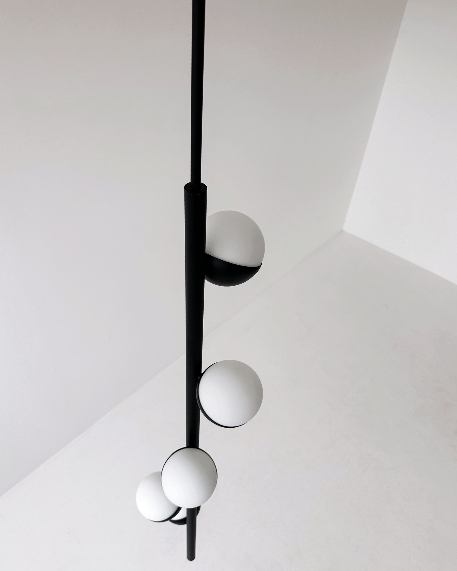 Dettaglio ravvicinato CRYSTAL TUBE: lampada a sospensione in ottone nero opaco con sfere di vetro Murano bianche, design minimale.